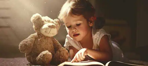 Kind ließt ein Kinderbuch mit Ihrem Teddy